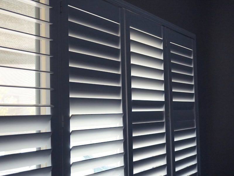 Dark room interior with sleek modern windows after installing plantation shutters.