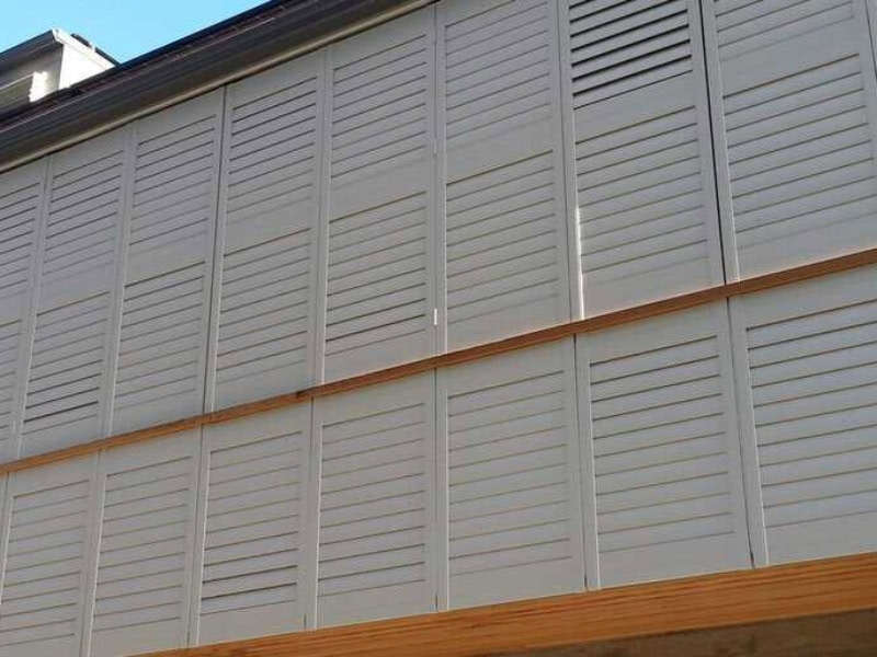 Modern home fitted with grey exterior shutters on windows across the upper floor