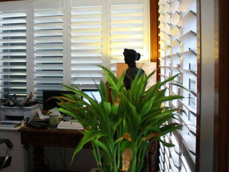 Home office brightened by installing plantation shutters on wide windows.