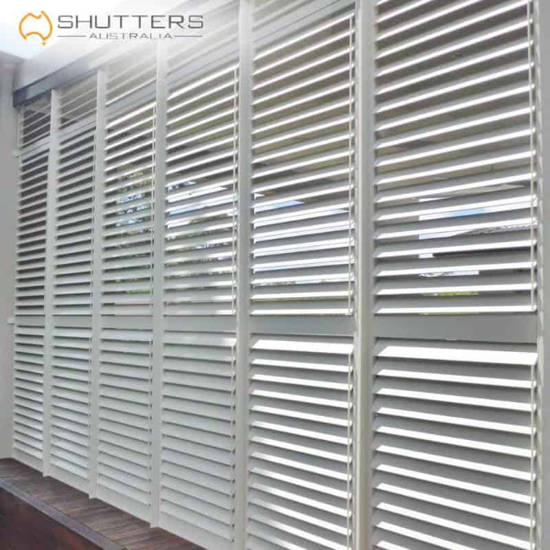 outdoor blinds nsw Outdoor blinds in NSW featuring white plantation shutters on an exterior wall, balancing light control, privacy, and modern style.