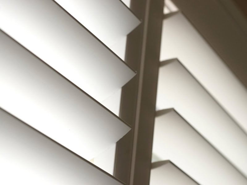 best interior shutters close-up of white plantation louvres angled open, showing smooth finish and light gaps.