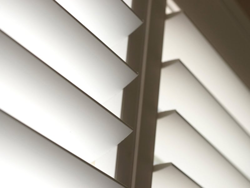 Close-up view showing installing interior window shutters with modern white louvres for light control.