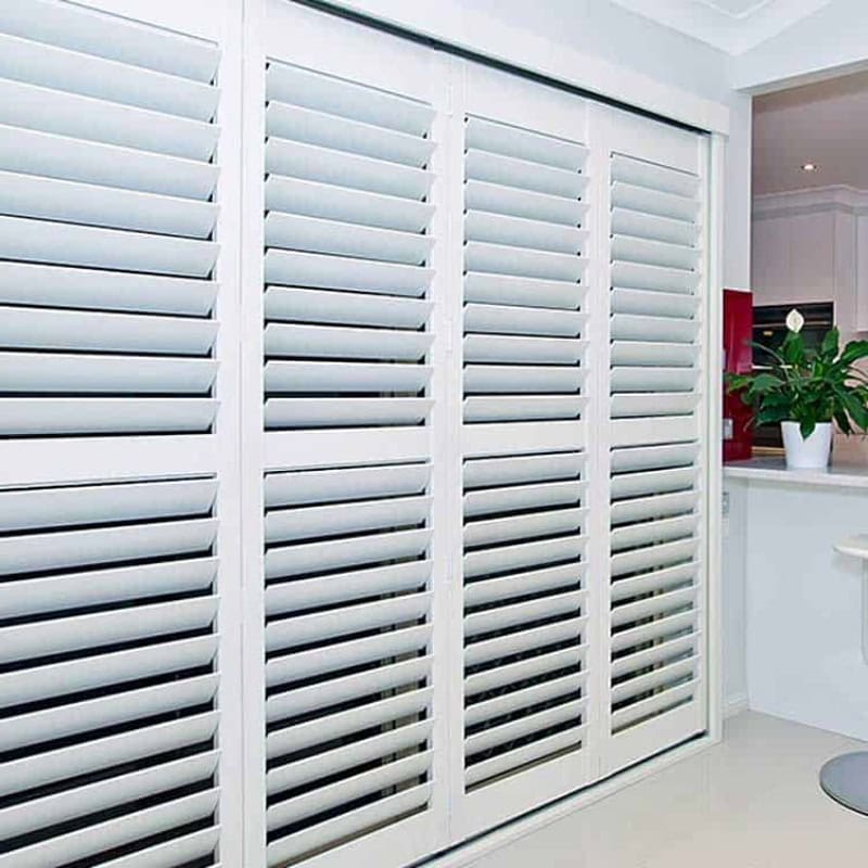 Plantation shutters installed on large indoor windows, featuring white adjustable louvres in a modern Australian home.