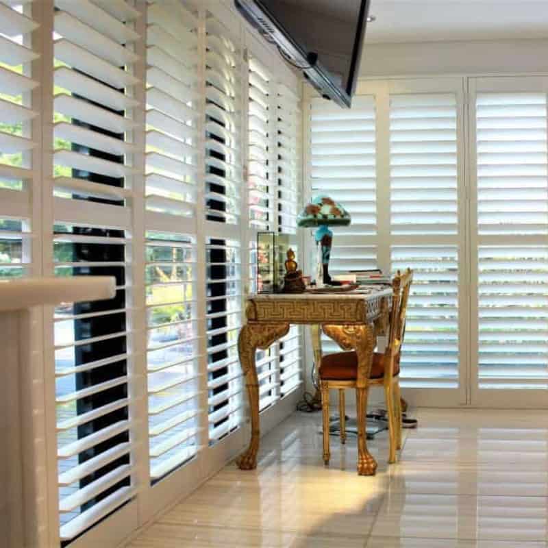 Plantation shutters installed on large interior windows, controlling light and privacy in a bright living space.