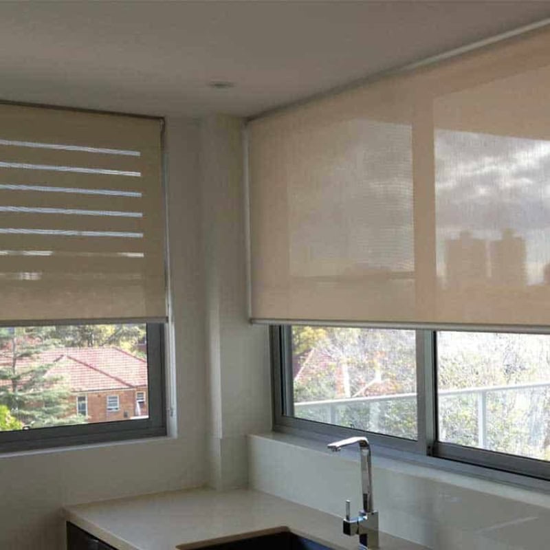 Roller blinds covering kitchen windows, reducing glare while maintaining privacy and filtered natural light.