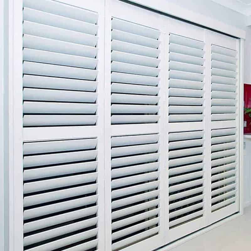Custom interior plantation shutters in a Sydney home, featuring four white timber panels with large louvres for light control.